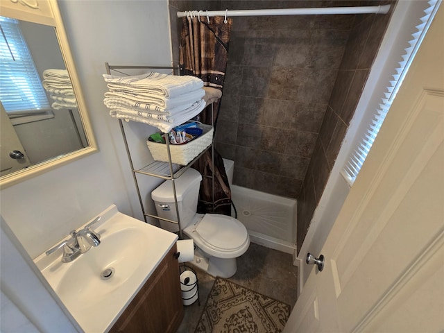 bathroom with a tile shower, vanity, and toilet