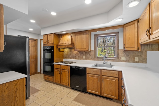 kitchen with a sink, premium range hood, tasteful backsplash, and black appliances