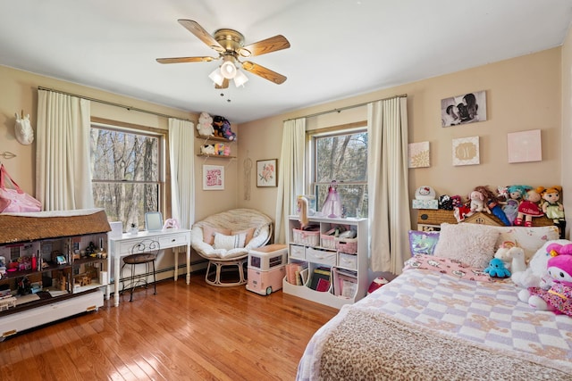 bedroom with ceiling fan, multiple windows, and wood finished floors