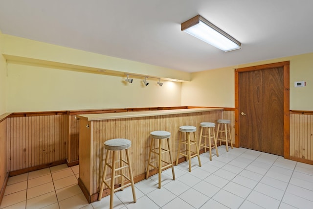 bar featuring track lighting, a wainscoted wall, and a bar
