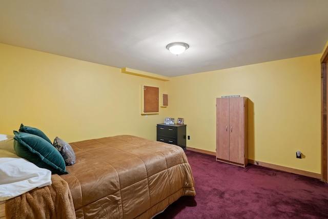 bedroom with dark colored carpet and baseboards