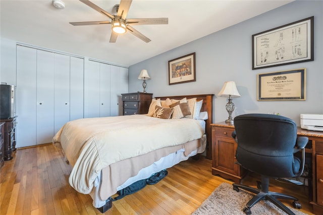 bedroom featuring wood-type flooring, a ceiling fan, and two closets