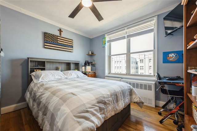 bedroom featuring baseboards, radiator heating unit, and hardwood / wood-style flooring