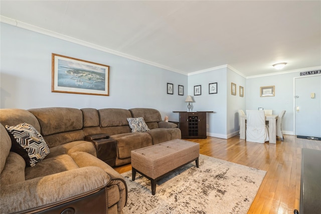 living area with ornamental molding, baseboards, and light wood-style flooring