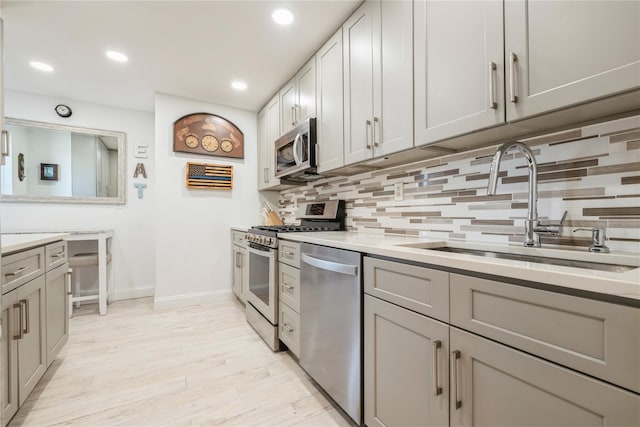 kitchen featuring a sink, baseboards, backsplash, light countertops, and appliances with stainless steel finishes