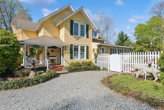 view of front of property with fence, covered porch, and a shingled roof