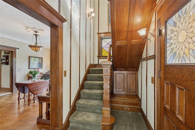 stairs featuring crown molding, wallpapered walls, and baseboards