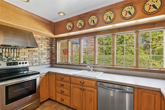 kitchen with a sink, light countertops, brown cabinetry, stainless steel appliances, and range hood
