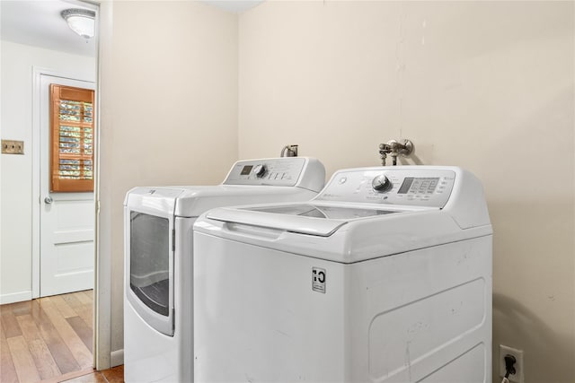 laundry area featuring separate washer and dryer, laundry area, and light wood-style flooring
