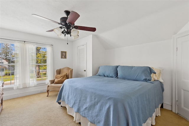 bedroom with a closet, a ceiling fan, lofted ceiling, and light carpet