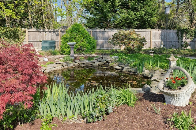 view of yard featuring fence and a small pond