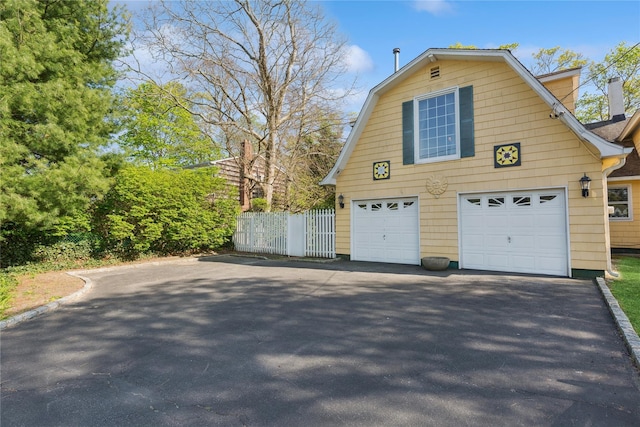 garage with aphalt driveway and fence
