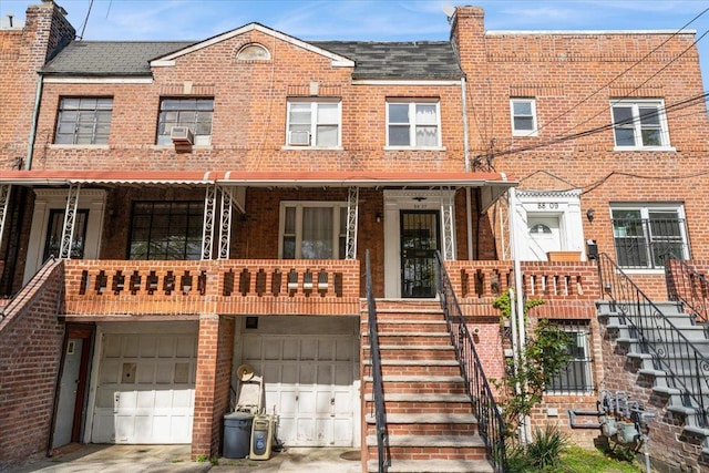 view of front of property with cooling unit, brick siding, an attached garage, driveway, and stairway