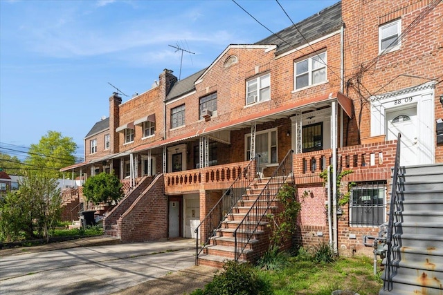 multi unit property with brick siding, stairway, and a porch