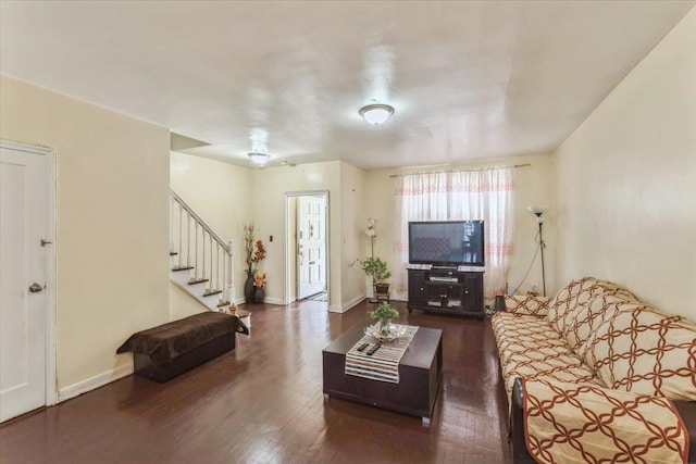 living room featuring baseboards, wood finished floors, and stairway