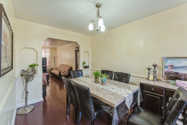 dining room featuring arched walkways, baseboards, and dark wood-style floors