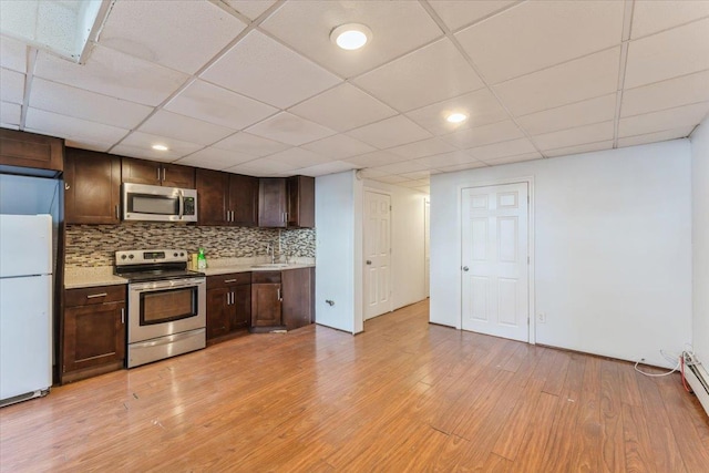 kitchen featuring dark brown cabinetry, light countertops, a sink, light wood-style flooring, and appliances with stainless steel finishes