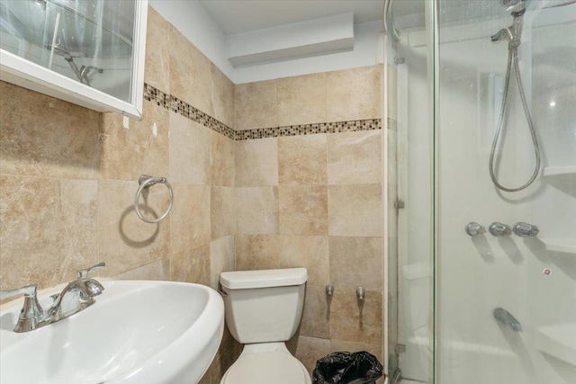 bathroom featuring a sink, tile walls, toilet, and a shower stall