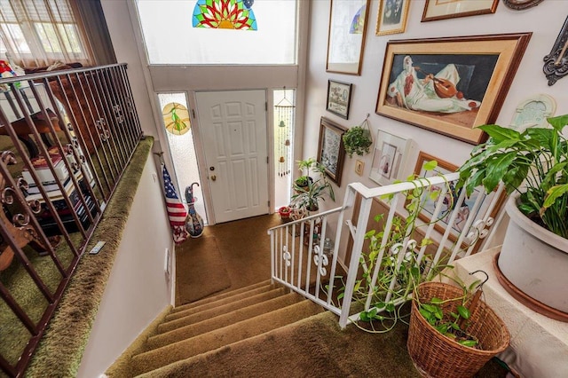 entryway featuring carpet floors, a high ceiling, and stairs