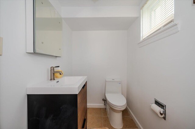 bathroom with baseboards, toilet, and vanity