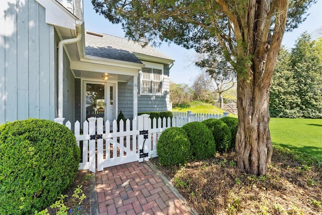 doorway to property with a gate, roof with shingles, and fence