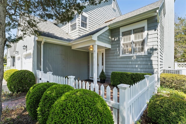bungalow featuring a shingled roof, an attached garage, and fence private yard
