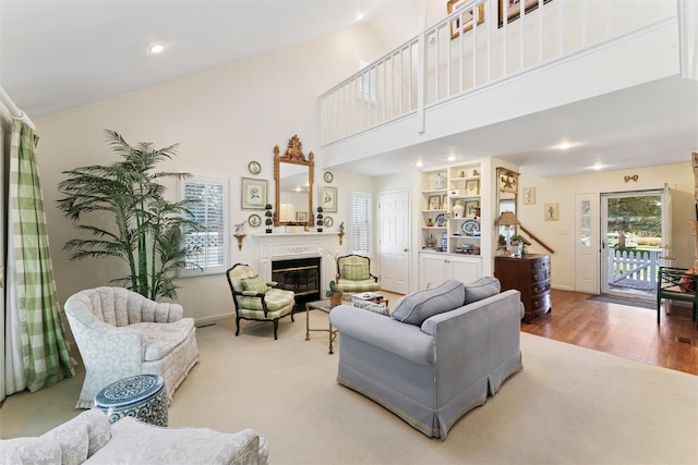 living room featuring a glass covered fireplace, a towering ceiling, wood finished floors, and a wealth of natural light