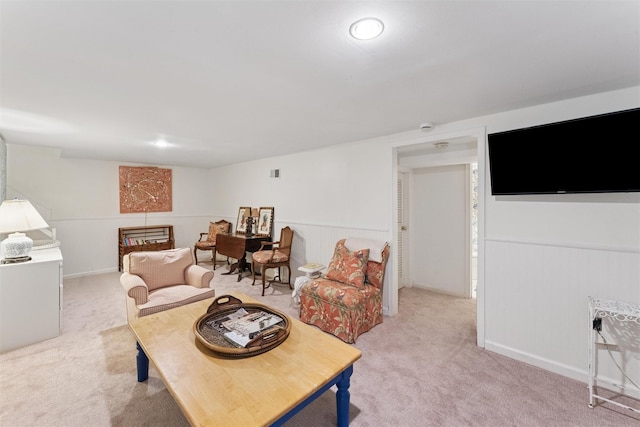 living area with wainscoting, visible vents, and light carpet