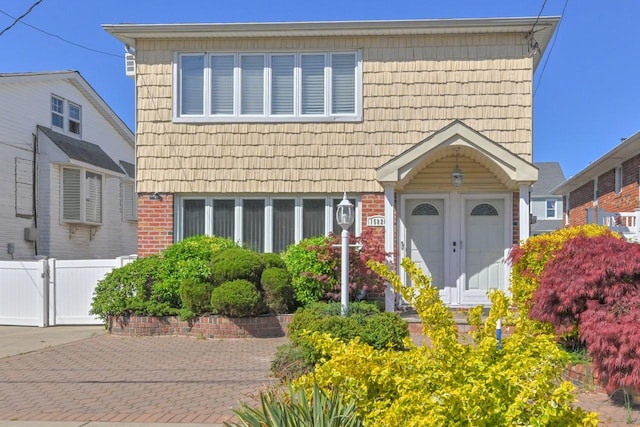 view of front facade featuring brick siding and fence