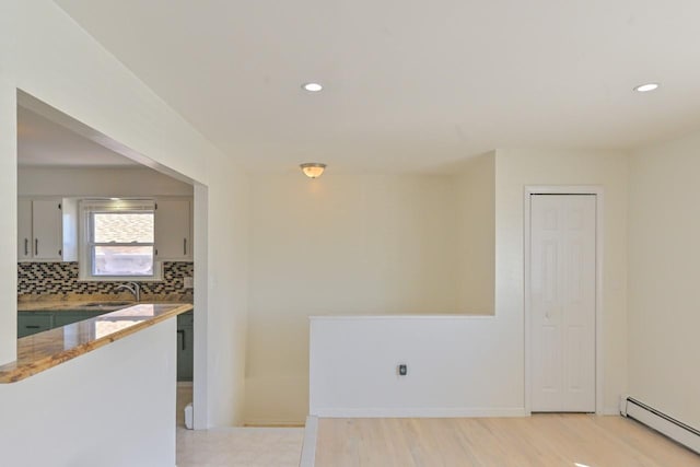 kitchen featuring light stone countertops, a sink, recessed lighting, tasteful backsplash, and a baseboard heating unit