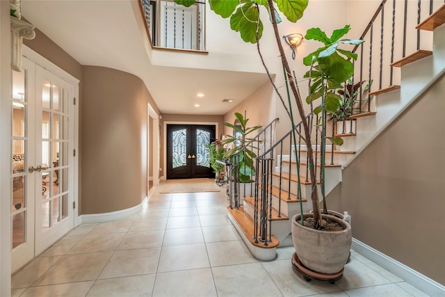 tiled entrance foyer with baseboards, french doors, and stairway