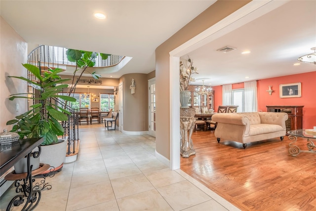 hall with an inviting chandelier, visible vents, light tile patterned flooring, baseboards, and recessed lighting