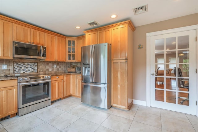 kitchen featuring stainless steel appliances, visible vents, stone counters, and tasteful backsplash