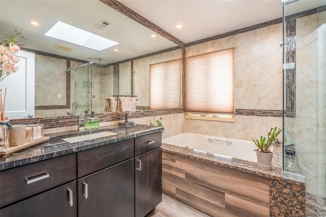 full bath with a bath, visible vents, a skylight, a shower stall, and vanity