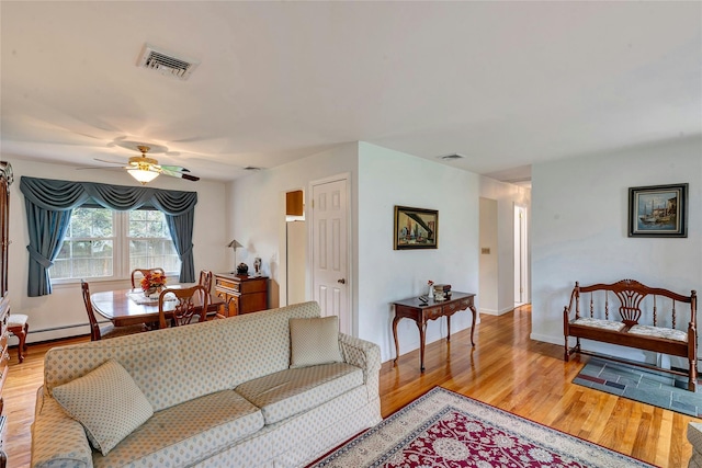 living room with visible vents, light wood-style flooring, ceiling fan, and baseboard heating
