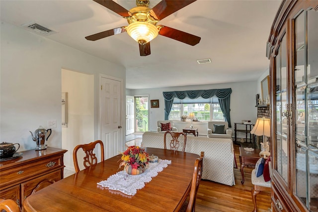 dining space with visible vents, a ceiling fan, and wood finished floors