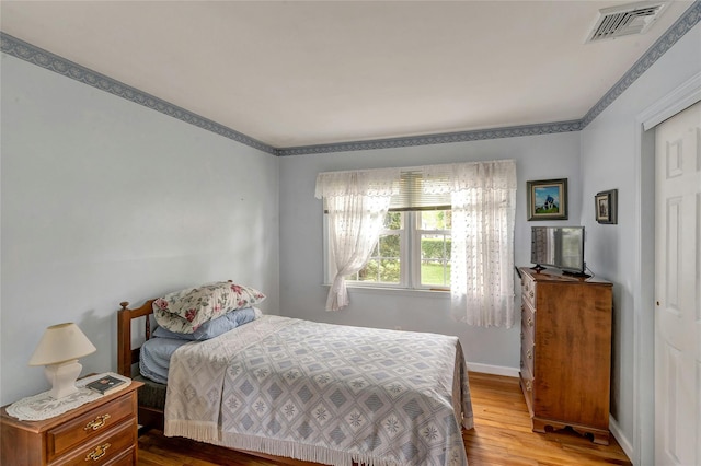 bedroom with visible vents, baseboards, and wood finished floors