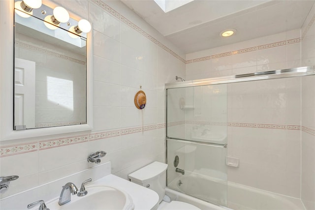 bathroom featuring tile walls, enclosed tub / shower combo, vanity, and toilet