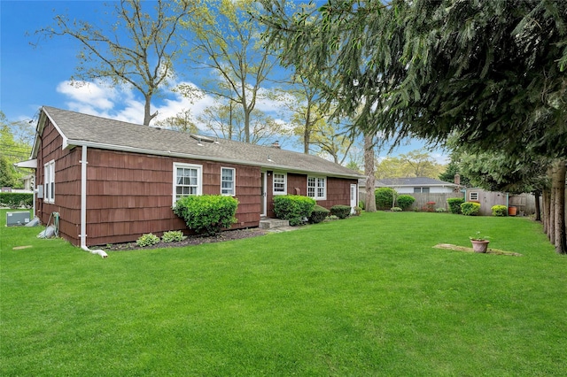 rear view of house featuring a fenced backyard, an outdoor structure, a lawn, and a shed