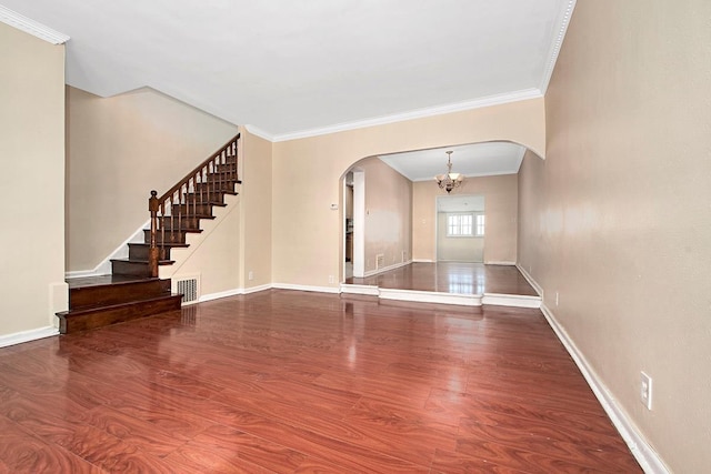 unfurnished living room featuring crown molding, arched walkways, wood finished floors, stairway, and a chandelier