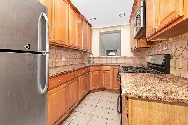 kitchen featuring a sink, decorative backsplash, stainless steel appliances, and light tile patterned flooring