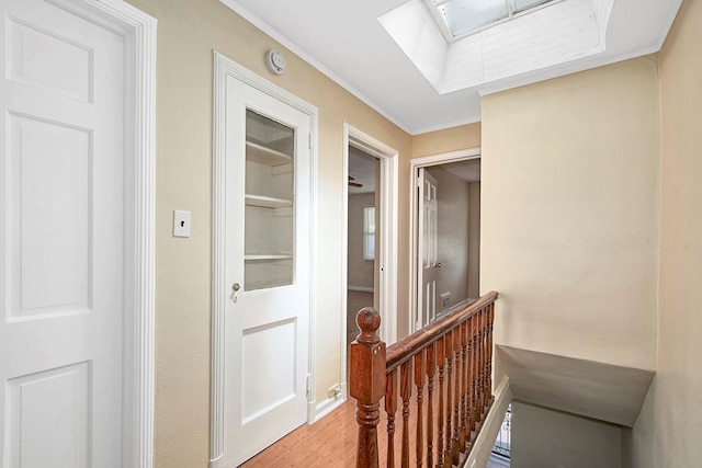 corridor with crown molding, attic access, wood finished floors, and an upstairs landing
