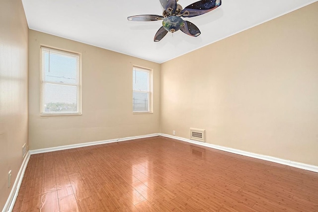 unfurnished room featuring baseboards, visible vents, and wood finished floors