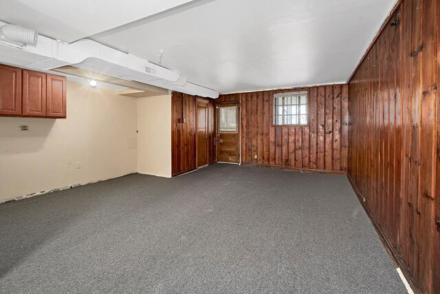 basement with wooden walls and dark carpet