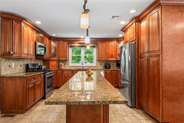 7 E Gate Ln, Setauket, NY 11733 - kitchen featuring appliances with stainless steel finishes, brown cabinets, decorative backsplash, dark stone countertops, and a center island