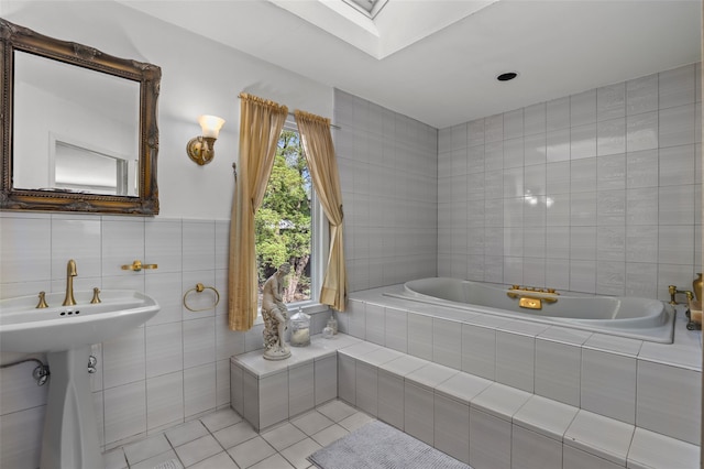 bathroom featuring a skylight, tile walls, tile patterned flooring, and a bath