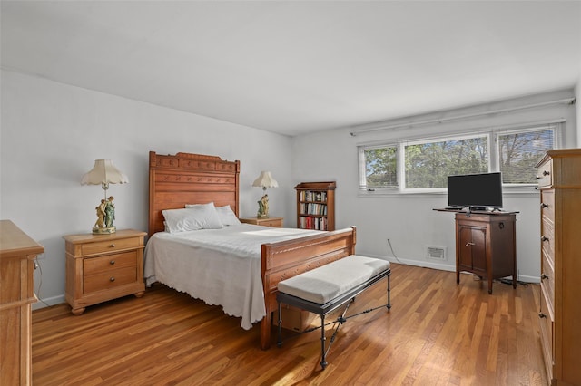 bedroom with visible vents, baseboards, and wood finished floors