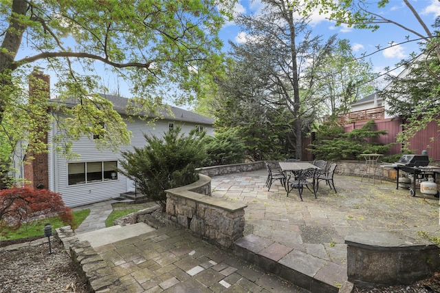 view of patio / terrace featuring fence, outdoor dining space, and a grill