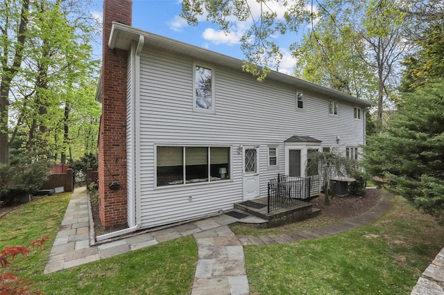rear view of house featuring a lawn, central AC, and a chimney