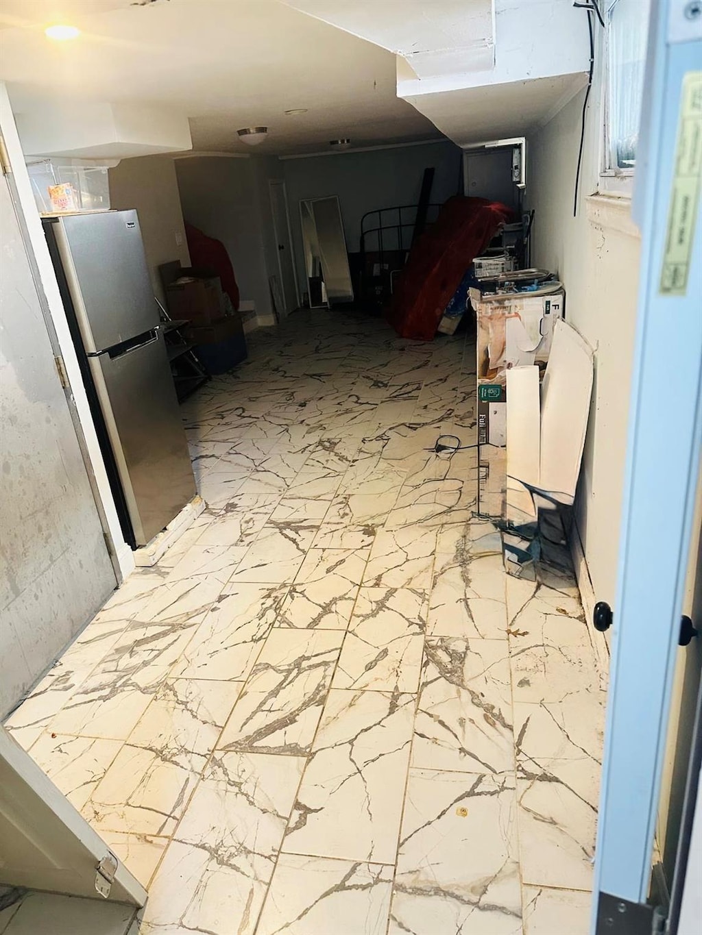 basement with freestanding refrigerator and marble finish floor
